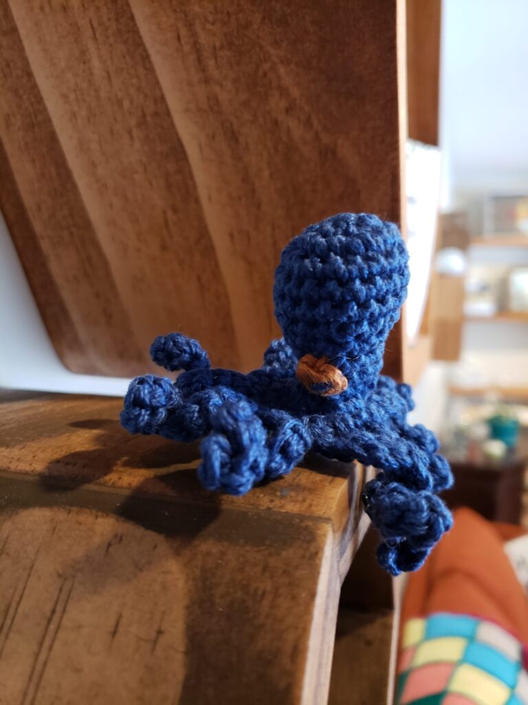 Tiny crocheted octopus on a shelf 2